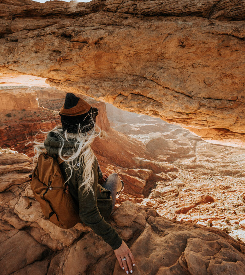 Girl Sitting on Edge at Mesa Arch Moab Utah Hiking Trail